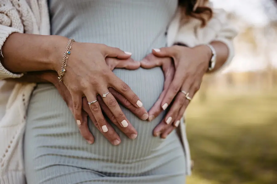 Hände formen ein Herz auf dem Babybauch